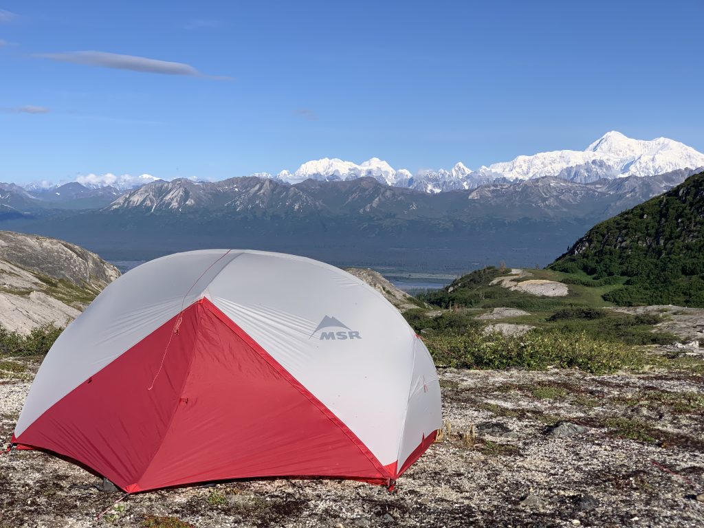 MSR tent pitched on rocky terrain with Denali and surrounding mountain range in the distance