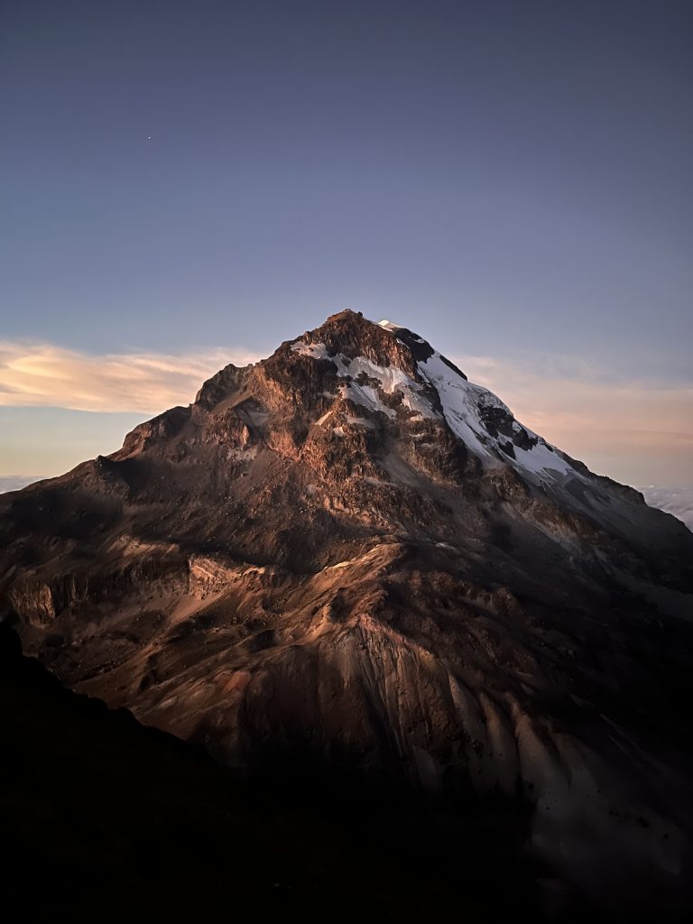 Illinizas South mountain at sunrise, bathed in warm light against a clear sky