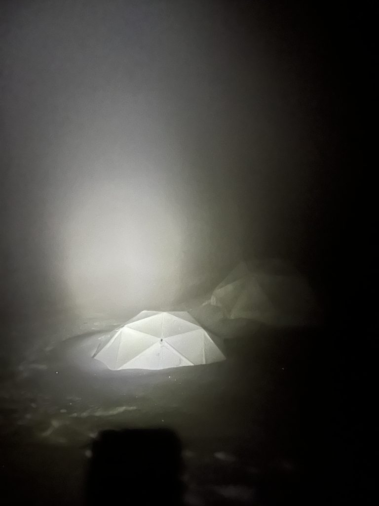 Tent illuminated in thick fog at night on Chimborazo