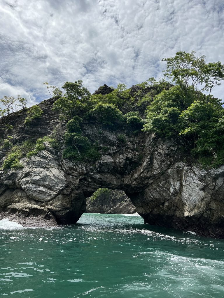 Rock formation with an arch surrounded by turquoise water in Costa Rica