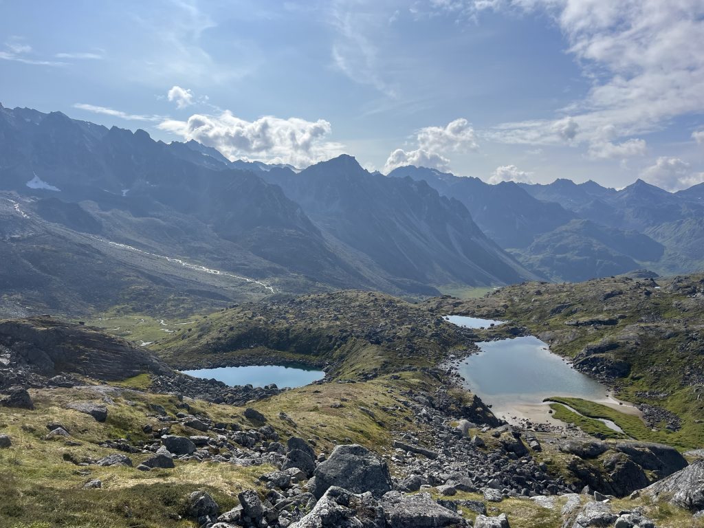 High-altitude alpine lakes surrounded by mountains under a partly cloudy sky