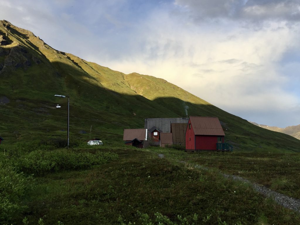 Red cabins nestled in a lush green valley with mountains in the background