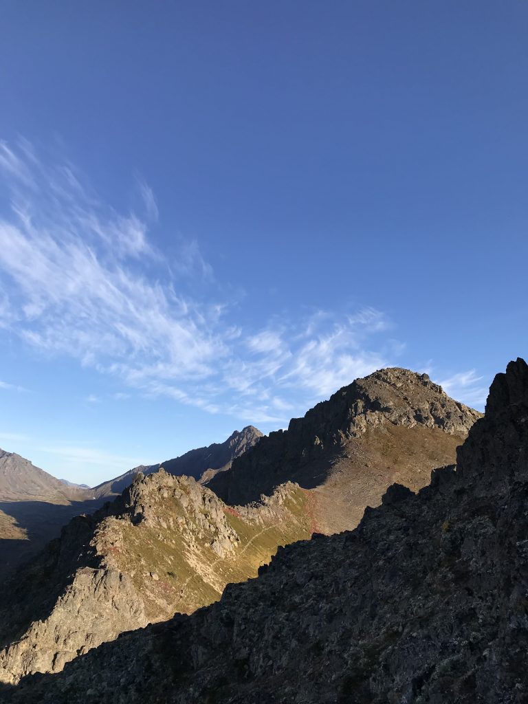 Rocky mountain landscape under a clear blue sky with scattered clouds