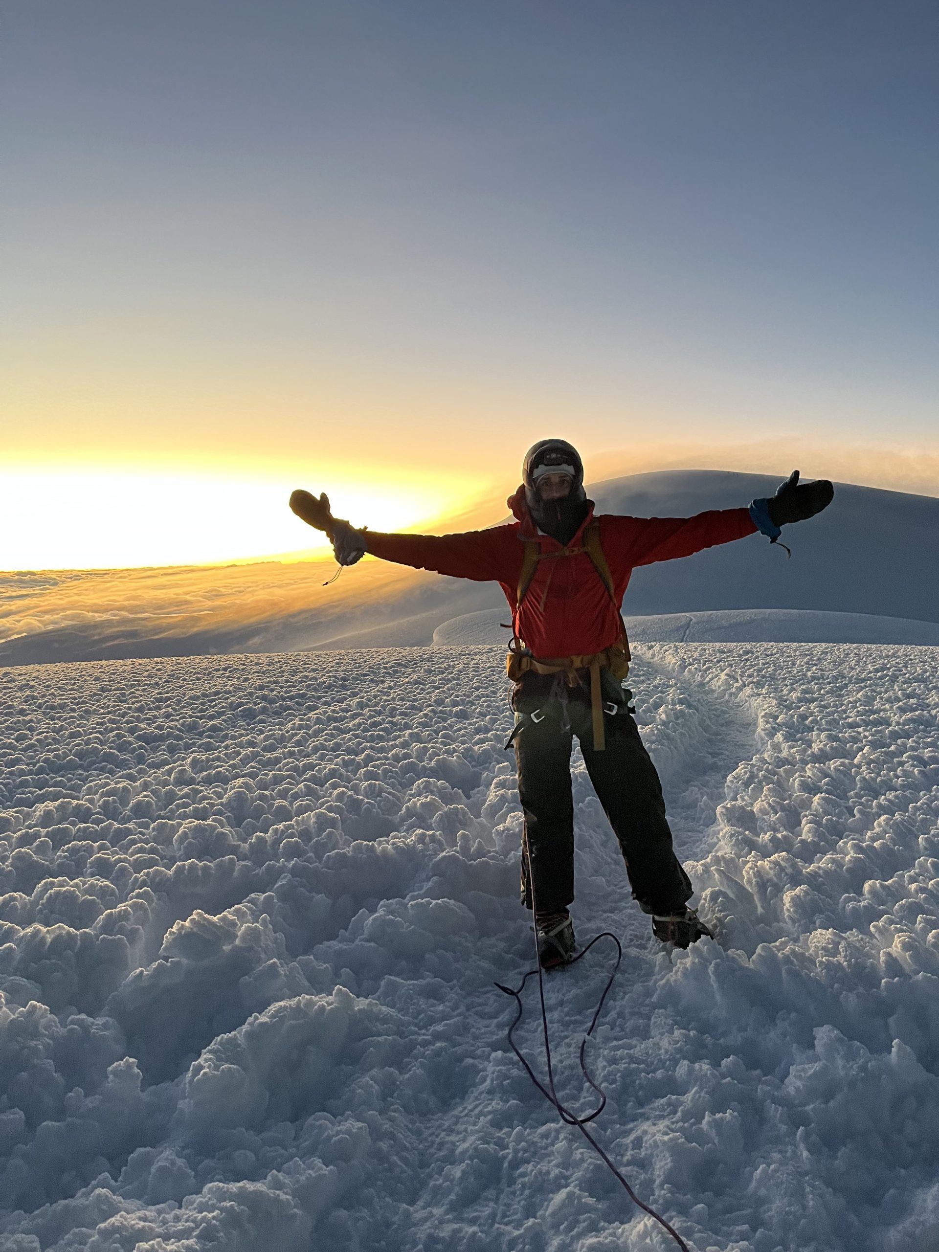 Climber at sunrise on Chimborazo with arms raised in celebration