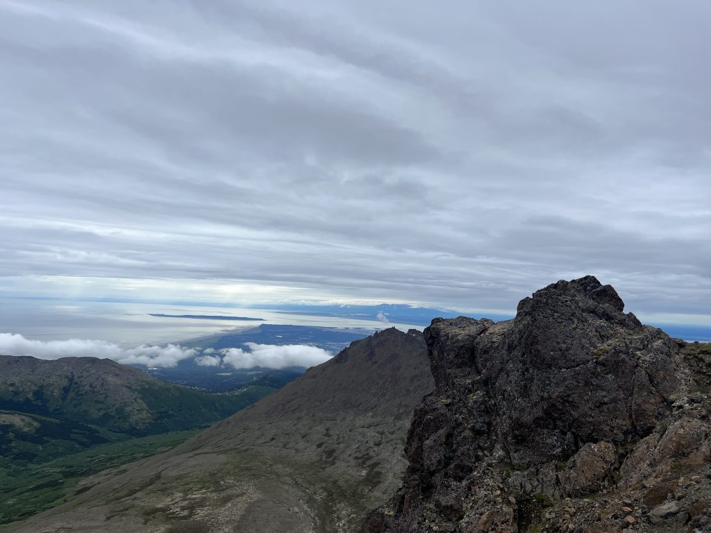 Rocky outcrop at the summit of Ptarmigan Peak, Anchorage, Alaska, overlooking Cook Inlet with clouds and open sky