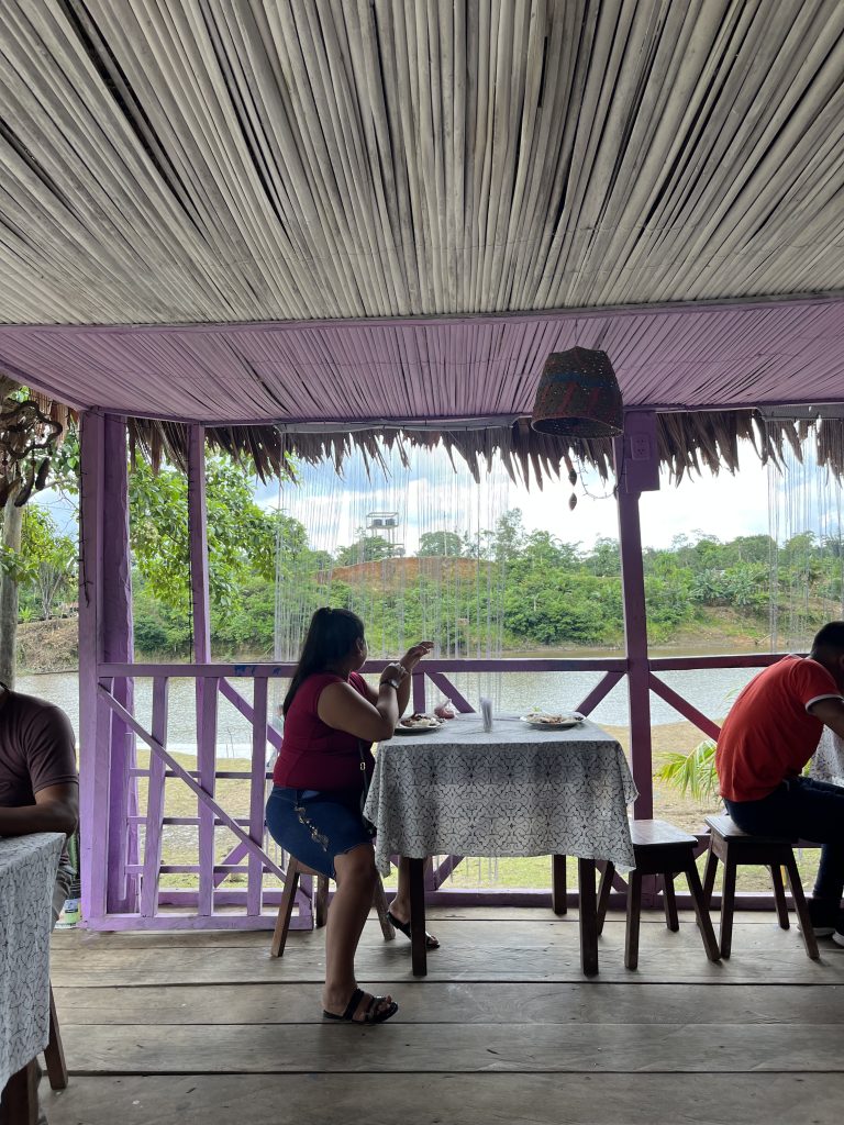 Local restaurant with open walls overlooking the Napo River, vibrant purple decor and locals dining