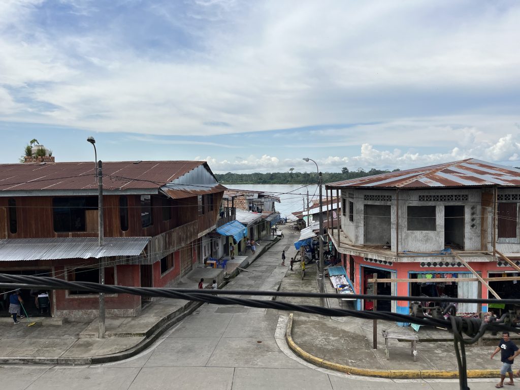 Street scene in Mazan along the Napo River, showcasing rustic buildings with metal roofs