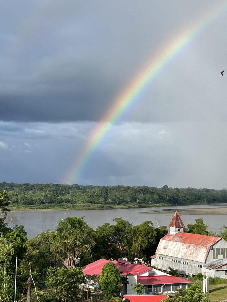 A vibrant rainbow stretches over the Napo River in Santa Clotilda, casting a colorful view over riverside buildings