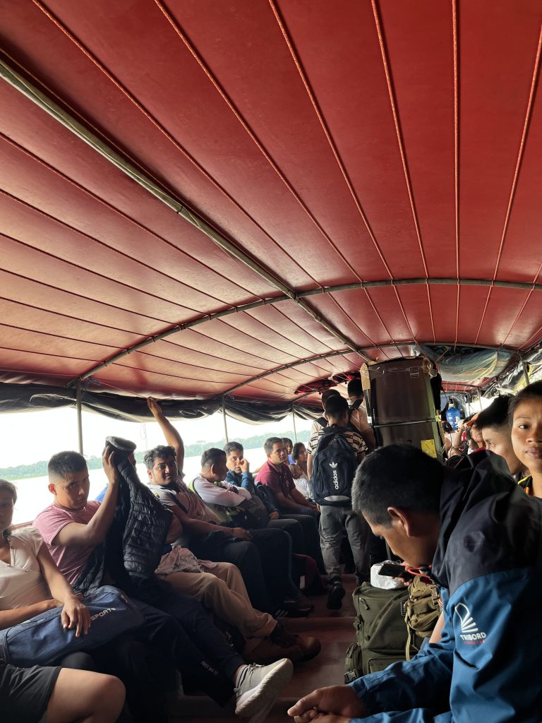 Interior of a crowded boat on the Napo River from Santa Coltida, locals sitting and standing under a red canopy