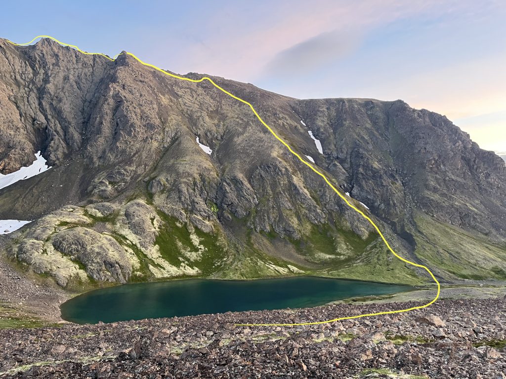 View of McHugh Lake with a yellow-marked route leading up the ridge above the lake, set against rugged terrain