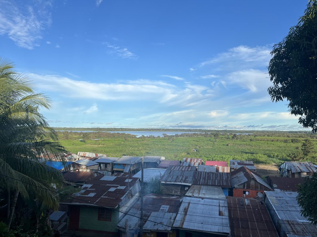 Panoramic view over rooftops on the Amazon River, with lush greenery and river stretching to the horizon in Iquitos