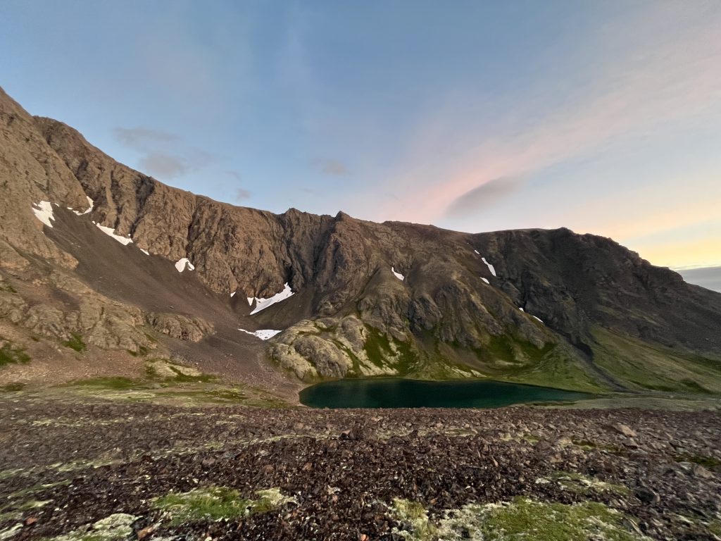 View of Rabbit Lake in Anchorage, Alaska, surrounded by rugged mountains at dusk