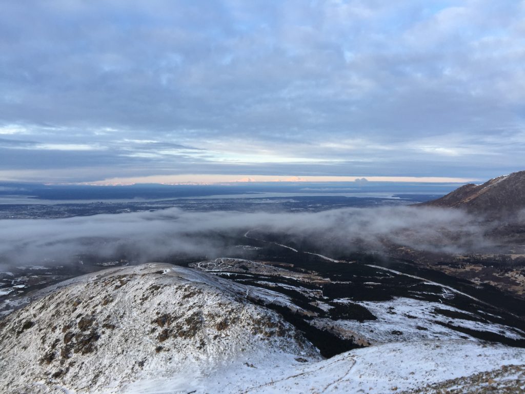 View from Flattop Mountain looking down at the first saddle in Anchorage, Alaska, with a winter landscape of snow-covered hills