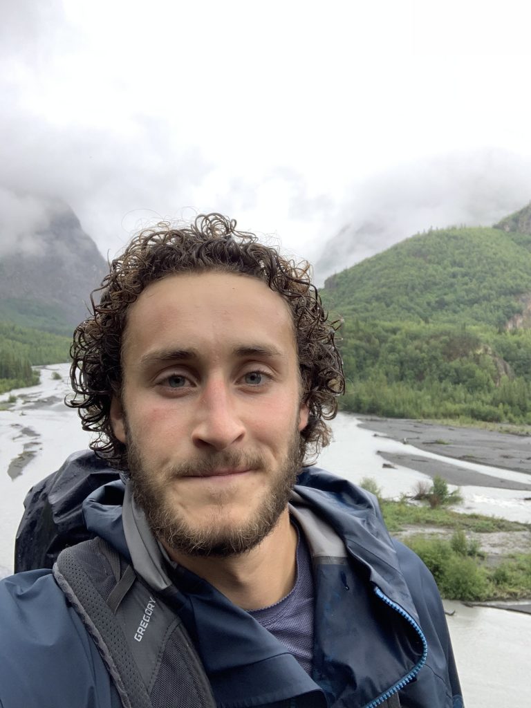 Noam on a trail in Alaska with a rain jacket